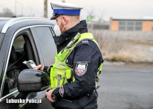 Policjant drogówki podczas sprawdzania trzeźwości kierującego pojazdu.