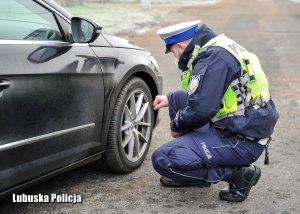 policjant kontroluje stan ogumienia pojazdu