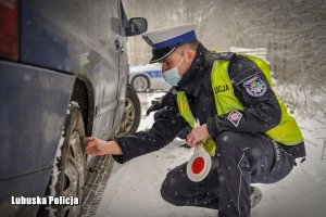 policjant kontroluje stan ogumienia pojazdu