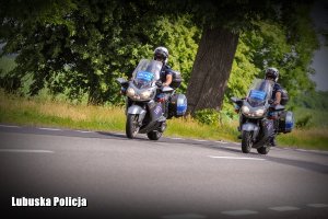 Motocykle policyjne jadące drogą.