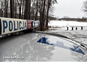 Policyjny radiowóz nad jeziorem w zimie.