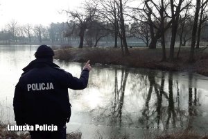 policjant wskazuje coś przy jeziorze