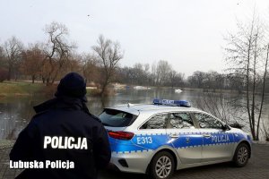 policjant i radiowóz przy jeziorze