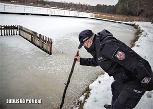 Policjant sprawdza grubość pokrywy lodowej na jeziorze.