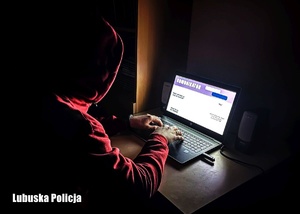 Mężczyzna w kapturze piszący na laptopie