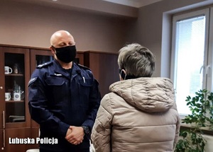 Policjant rozmawia ze starszą kobieta w pomieszczeniu.