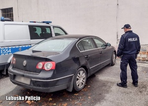 Policjant stojący obok pojazdu.