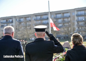 Mundurowy salutuje przy podnoszonej fladze Polski