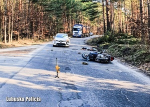 Miejsce wypadku drogowego - na jezdni widać samochód osobowy i motorower.