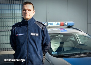 Policjant stojący przy radiowozie.