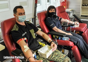 Policjantka i strażnik graniczny podczas oddawania krwi w krwiobusie.
