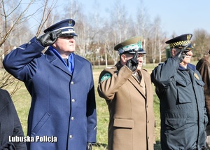 Przedstawiciele służb mundurowych oddają hołd podczas hymnu państwowego.