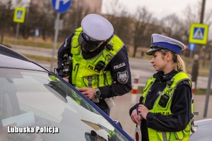 Policjant i policjantka zatrzymują pojazd do kontroli