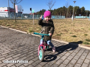 Dziewczynka na rowerze z przekazanym odblaskiem od policjantów