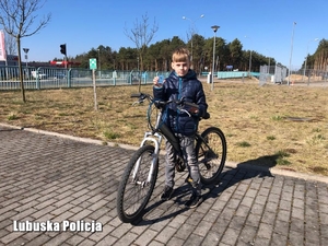 Chłopiec na rowerze z przekazanym odblaskiem od policjantów