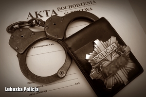Kajdanki i odznaka policyjna na teczce z dokumentami