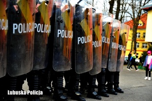 Policjanci oddziałów prewencji w szeregu z tarczami