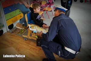 Policjant drogówki rozmawia z małych chłopcem w przedszkolu.