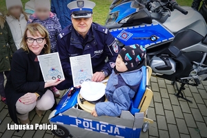 Policjant z dziećmi pozują do zdjęcia przy radiowozie policyjnym.