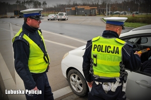 Policjanci drogówki podczas kontroli drogowej pojazdu osobowego.