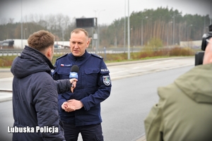 Policjant udziela wywiadu dziennikarzowi przy drodze ekspresowej.
