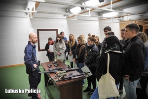 Policyjny instruktor prezentuje uczniom różne rodzaje broni na strzelnicy.