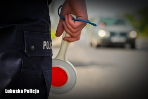 policjant trzyma tabliczkę do zatrzymywania pojazdów