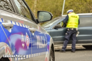 radiowóz i policjant kontrolujący pojazd