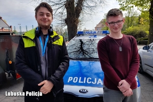 Dwóch młodych mężczyzn przy policyjnym radiowozie