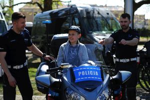 Policjanci i chłopiec siedzący na motocyklu.