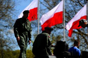 Żołnierze na czołgu, a w tle flagi Polski.