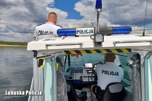 policjanci obserwują jezioro z pokładu łodzi
