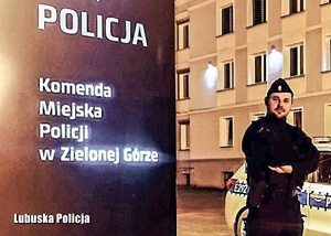 Umundurowany policjant stojący przy banerze.