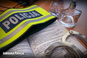 Perfumy, opaska policyjna i kodeks na policyjnym biurku
