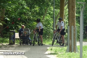 policyjny patrol rowerowy rozmawia z osobami w parku