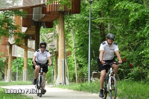 policyjny patrol rowerowy jedzie przez park