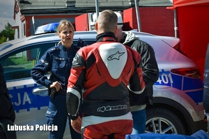 Policjantka rozmawia z motocyklistą przy stoisku promocyjnym