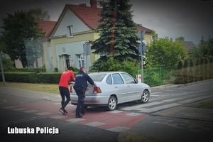 policjant i mężczyzna pchają samochód