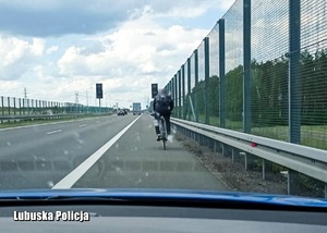 Rowerzysta jadący pasem awaryjnym po drodze ekspresowej.