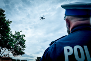 Policjant drogówki, a w tle, na niebie dron powietrzny.