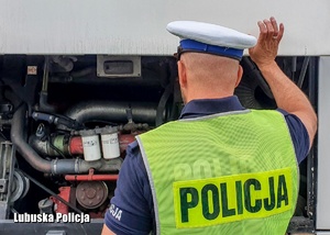 Policjant drogówki sprawdzający stan techniczny autobusu.