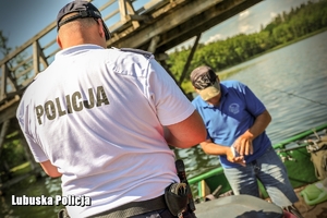 policjant na łodzi sprawdza dokumenty wędkarza