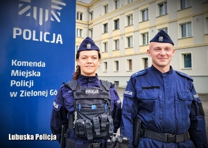 Umundurowanie policjanci, a w tle budynek komendy Policji.