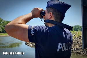 Policjant patrzy przez lornetkę na wodę