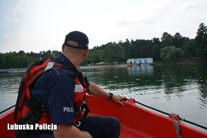 policjant na łodzi obserwuje jezioro