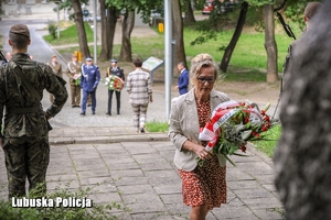 kobieta niesie kwiaty w kierunku pomnika