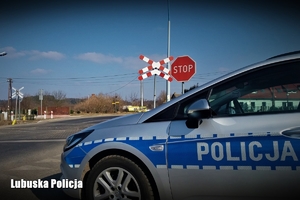 Policyjny radiowóz przy torowisku na tle znaku STOP