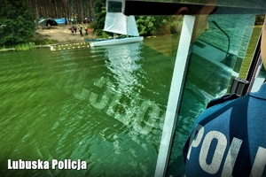 Policjant patroluje w łodzi brzeg akweny