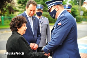 Inspektor Jarosław Pasterski podaje rękę starszej kobiecie.