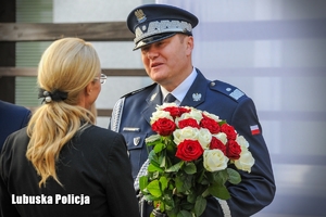 Nadinspektor odbiera wiązankę kwiatów od kobiety